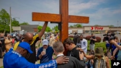 FILE - A group prays at the site of a memorial for the victims of the Buffalo supermarket shooting outside the Tops Friendly Market on May 21, 2022, in Buffalo, N.Y.