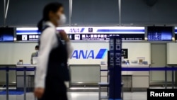 一名员工在新冠疫情爆发后戴着口罩，经过日本大阪关西机场几乎没有人的全日空柜台。