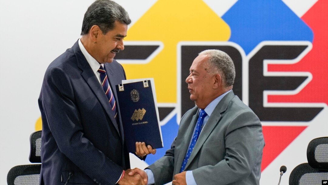 El presidente venezolano Nicolás Maduro estrecha la mano del presidente del CNE, Elvis Amoroso, al recibir su proclamación como ganador de la elección del 28 de julio de 2024, durante un acto celebrado un día después en Caracas.