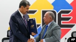 El presidente venezolano Nicolás Maduro estrecha la mano del presidente del CNE, Elvis Amoroso, al recibir su proclamación como ganador de la elección del 28 de julio de 2024, durante un acto celebrado un día después en Caracas.