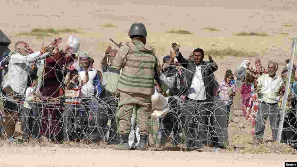 A Turkish soldier stands guard as Syrian Kurds wait behind the border fence to cross into Turkey near the southeastern town of Suruc in Sanliurfa province, Sept. 19, 2014. 