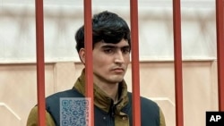 In this photo released by the Basmanny District Court press service on April 27, 2024, Dzhumokhon Kurbonov, a suspect in the Crocus City Hall shooting, stands in a cage in court in Moscow, Russia.