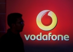 FILE PHOTO: A man casts silhouette onto an electronic screen displaying logo of Vodafone India after a news conference in Mumbai, India, Nov. 10, 2015.