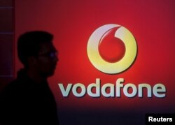 FILE PHOTO: A man casts silhouette onto an electronic screen displaying logo of Vodafone India after a news conference in Mumbai, India, Nov. 10, 2015.