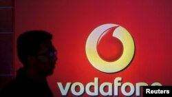 FILE PHOTO: A man casts silhouette onto an electronic screen displaying logo of Vodafone India after a news conference in Mumbai, India, Nov. 10, 2015. 