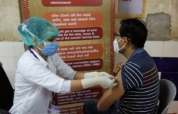 FILE - A health worker administers a COVID-19 vaccine to a hospital staff at a vaccination center in Ahmedabad, India, Jan. 28, 2021.