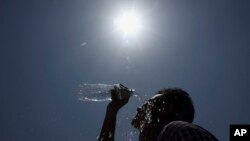 FILE - An Indian man pours water on his face during a hot summer day in Hyderabad, India, May 24, 2015. 