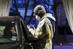 FILE - Certified nursing assistant (CNA) Jermaine LeFlore prepares to take a patient's nasal swab at a drive-thru testing site outside the Southside Health Center in Milwaukee, Wisconsin, Oct. 21, 2020.