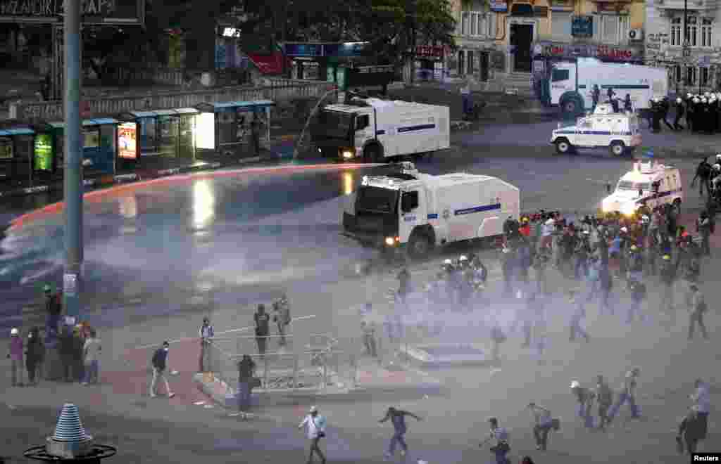 People run as riot police fire a water cannon on Gezi Park protesters at Taksim Square in Istanbul, June 15, 2013. 