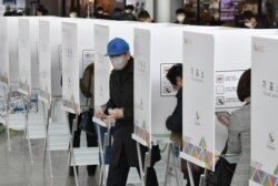 FILE - A South Korean man casts a ballot during early voting ahead of next week's parliamentary elections, at a polling station in Seoul.