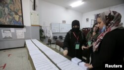 Electoral workers with protective masks are seen at a polling station during the parliamentary election, in Algiers, Algeria, June 12, 2021.