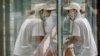 A delivery courier wearing a face mask to protect against COVID-19 is reflected in a window glass as she walks into a restaurant in Beijing, July 27, 2021. 