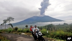 Motorists ride past by as Mount Marapi spews volcanic materials during its eruption in Agam, West Sumatra, Indonesia, Dec. 4, 2023. 