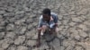 FILE - In this file photo taken Sunday Jan. 29, 2016, Last Zimaniwa feels the broken ground at a spot which is usually a reliable water source that has dried up due to lack of rains in the village of Chivi , Zimbabwe.