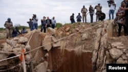 People watch and wait outside a mineshaft where it is estimated that hundreds of illegal miners are believed to be hiding underground, after police cut off food and water as part of police operations against illegal miners in Stilfontein, South Africa, on Nov. 15, 2024.