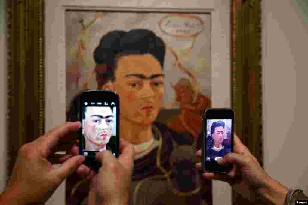 Visitors take pictures of the painting 'Autoportrait au Petit Singe' by Mexican artist Frida Kahlo (1907-1954) during the presentation of the exhibition 'Frida Kahlo/Diego Rivera, Art in Fusion' at the Musee de l'Orangerie in Paris, France.