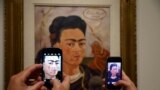 Visitors take pictures of the painting 'Autoportrait au Petit Singe' by Mexican artist Frida Kahlo (1907-1954) during the presentation of the exhibition 'Frida Kahlo/Diego Rivera, Art in Fusion' at the Musee de l'Orangerie in Paris, France.