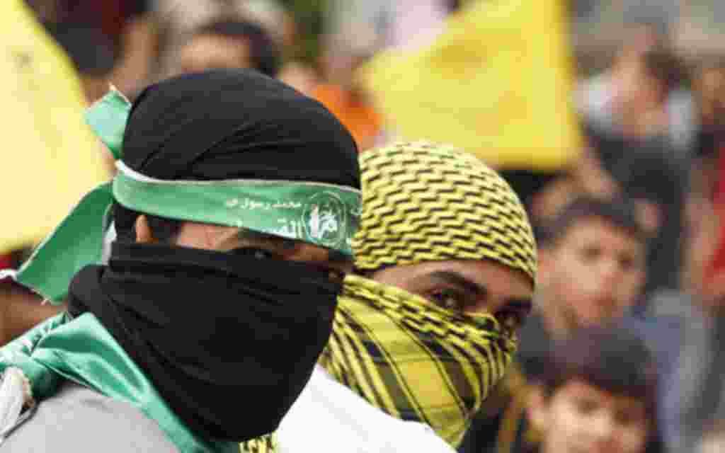 Palestinians wearing Hamas (L) and Fatah masks celebrate the reconciliation agreement between rival Palestinian factions Fatah and Hamas in a street in Gaza City May 4, 2011. Palestinian leaders formally ended a four-year rift between secular Fatah and th