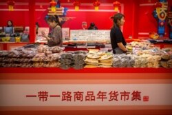 FILE - Clerks stand at a display of goods at a Belt and Road Products New Year's Marketplace at a shopping mall in Beijing, Jan. 10, 2020. The market showcases products created from countries and regions involved in China's Belt and Road Initiative.