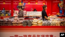 Clerks stand at a display of goods at a "Belt and Road Products New Year's Marketplace" at a shopping mall in Beijing, Jan. 10, 2020. The market showcases products created from countries and regions involved in China's Belt and Road Initiative.