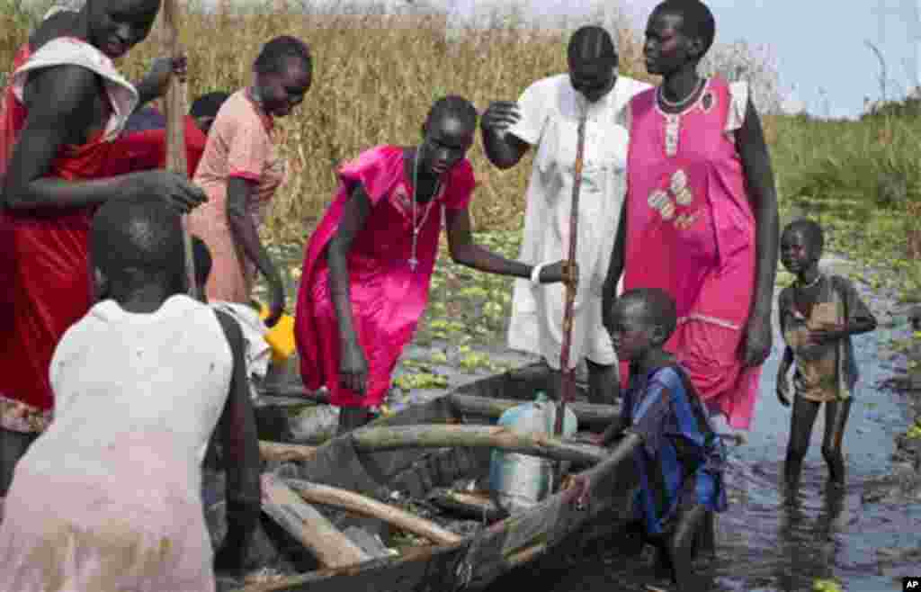 Une famille de l&rsquo;ethnie Nuer à la recherche des mécadiments et de la nourriture, mais qui doit regagner leur village dans la zone contrôlée par des rebelles, prépare d&rsquo;embarquer dans un canoë pour traverser une zone inondée où elle sera contrainte de marcher dans le marécage près de la Mission Onusienne au Sud Soudan (UNMISS) au village de Bentiu, au Sud Soudan. 