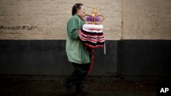 Janette Vorster of the 'Hurst Hookers' knitting group carries a crocheted crown made as a post box topper during a pre-coronation 'yarn bombing' in the village of Hurst, near Reading, England, April 21, 2023.