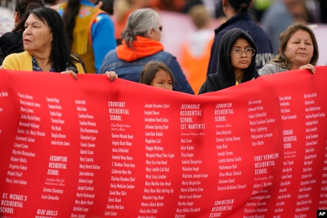 Indigenous people hold up a banner while waiting for Pope Francis during his visit to Maskwaci, the former Ermineskin Residential School, Monday, July 25, 2022, in Maskwacis, Alberta. Pope Francis traveled to Canada to apologize to Indigenous peoples for the abuses committed by Catholic missionaries in the country's notorious residential schools. (AP Photo/Eric Gay)