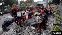 Regu penyelamat membersihkan reruntuhan yang mengubur kendaraan-kendaraan pasca gempa di kota Cebu, Filipina (15/10).