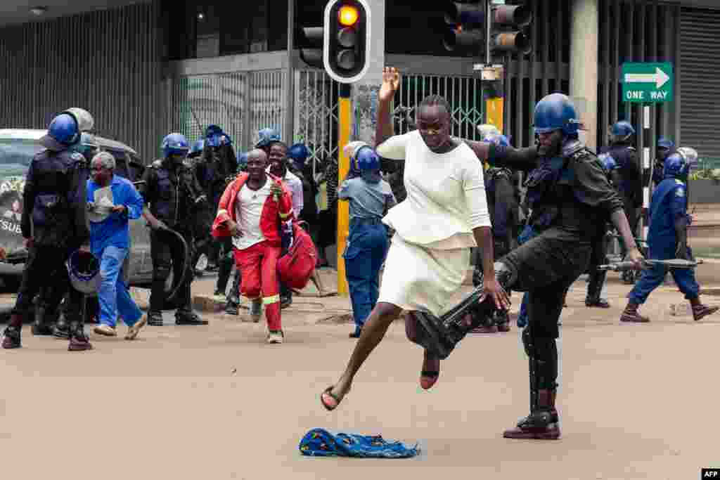 An anti-riot policeman tackles a woman as they disperse a crowd gathered to hear an address by Nelson Chamisa, leader of the MDC (Movement for Democratic Change) Alliance, at Morgan Tsvangirai House, the party headquarters in Harare, Zimbabwe.