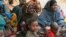 FILE - Somali women and children sit under a tree at a refugee camp in Dolo, Somalia while waiting for food rations.