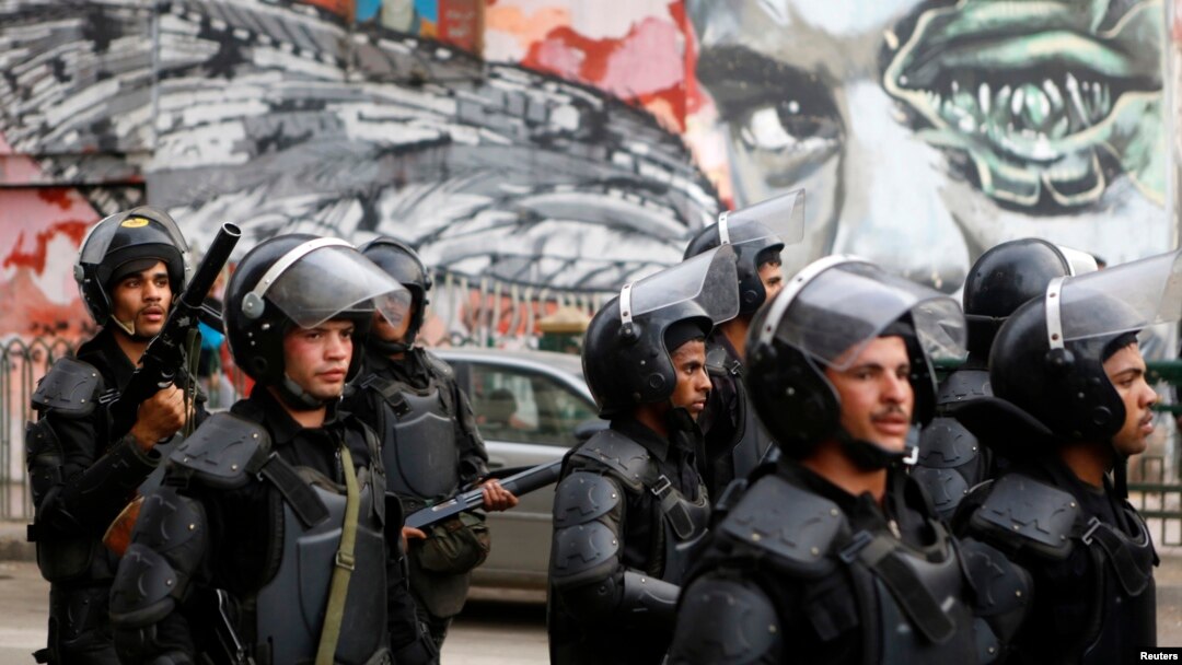 Riot police walk in front of graffiti depicting Bassem Mohsen, 20, who was killed in the 2011 Egypt uprising, along Mohamed Mahmoud street during the third anniversary of violent and deadly clashes near Tahrir Square in Cairo, Nov. 19, 2014.