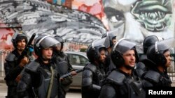 Riot police walk in front of graffiti depicting Bassem Mohsen, 20, who was killed in the 2011 Egypt uprising, along Mohamed Mahmoud street during the third anniversary of violent and deadly clashes near Tahrir Square in Cairo, Nov. 19, 2014.