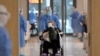 FILE - A medical worker in a protective suit moves a coronavirus patient in a wheelchair at a hospital in Wuhan, Hubei province, China, Feb. 10, 2020.