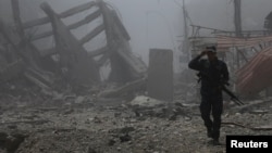 FILE - A member of the Iraqi Federal Police walks by destroyed buildings from clashes in the Old City of Mosul, Iraq, July 10, 2017. 