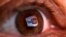 FILE - A reflection of YouTube's logo is seen in a person's eye.