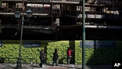 Pedestrian walks outside an abandoned building in central Athens, Feb. 26, 2018.