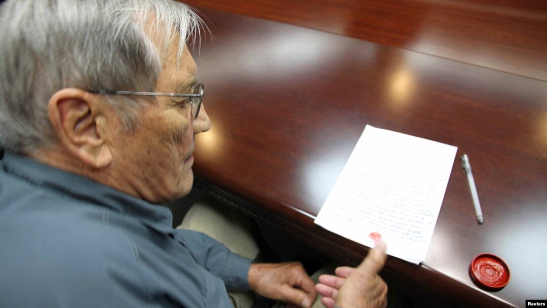 Esta foto muestra a Merrill Newman cuando estampa su huella digital en un documento preparado por Corea del Norte.