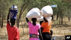 FILE - Women and girls walk back after getting food in Bentiu, a 38-kilometer (24-mile) journey using a path through the bush for fear of being attacked on the main road.