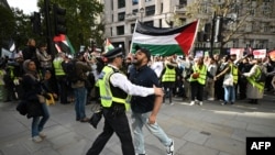 Petugas kepolisian menahan seorang aktivis pro-Palestina yang mencoba mendekat ke arah demonstran pro-Israel dalam aksi unjuk rasa untuk Palestina di London, pada 5 Oktober 2024. (Foto: AFP/Justin Tallis)