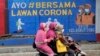 Perempuan muslim mengendarai motor di depan mural bertema virus corona di Jakarta (dok: AP)