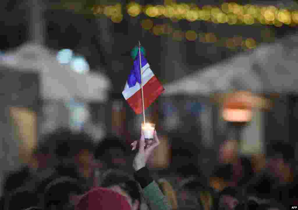 A member of the French community holds up a candle and a national flag during a vigil in Sydney on July 15, 2016.