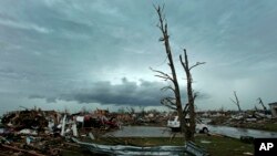 Awan badai di kejauhan di belakang rumah-rumah yang rusak karena tornado di Moore, Oklahoma (21/5). (AP/Charlie Riedel)