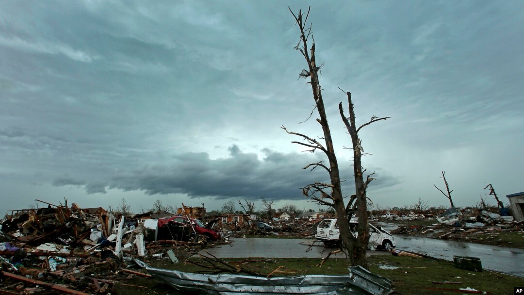 Awan badai di kejauhan di belakang rumah-rumah yang rusak karena tornado di Moore, Oklahoma (21/5). (AP/Charlie Riedel)
