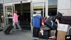 FILE - A baggage cart sits outside a terminal at Los Angeles International Airport in Los Angeles, March 27, 2014.