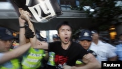 Một người biểu tình ủng hộ dân chủ bị cảnh sát bắt sau khi ông nhảy qua hàng rào an ninh, trong cuộc biểu tình trước khách sạn nơi ông Hồ Cẩm Đào ở, ở Hong Kong