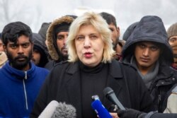 FILE - Surrounded by migrants, Dunja Mijatovic, the Council of Europe commissioner for human rights, addresses reporters at the Vucjak refugee camp outside Bihac, northwestern Bosnia, Dec. 3, 2019.