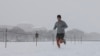 Um homem corre ao longo do National Mall enquanto a neve cai durante uma tempestade de inverno em Washington DC, a 6 de janeiro de 2025.