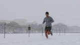 Um homem corre ao longo do National Mall enquanto a neve cai durante uma tempestade de inverno em Washington DC, a 6 de janeiro de 2025.