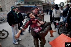 FILE - Man carries a boy who was severely wounded during heavy fighting between Syrian rebels and Syrian Army forces in Idlib, north Syria.