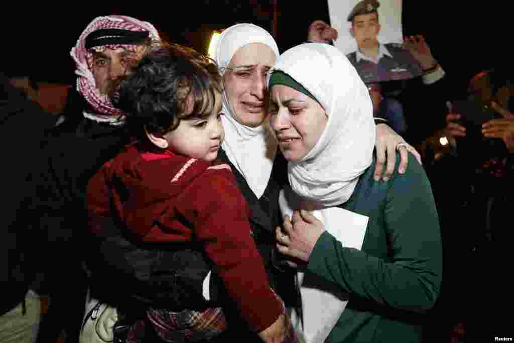 Anwar Tarawneh (phải), vợ của phi công Muath al-Kasaesbeh, và người chị em của anh ôm nhau khóc tại Amman.